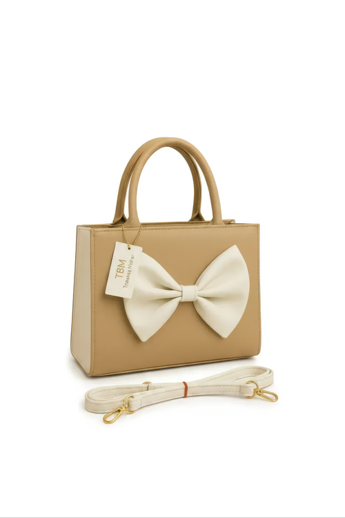 The Beige Bow Shoulder Bag is a small beige leather bag featuring rounded handles, a large cream bow accent on the front, a matching detachable strap, and a TBM Timeless by M tag.